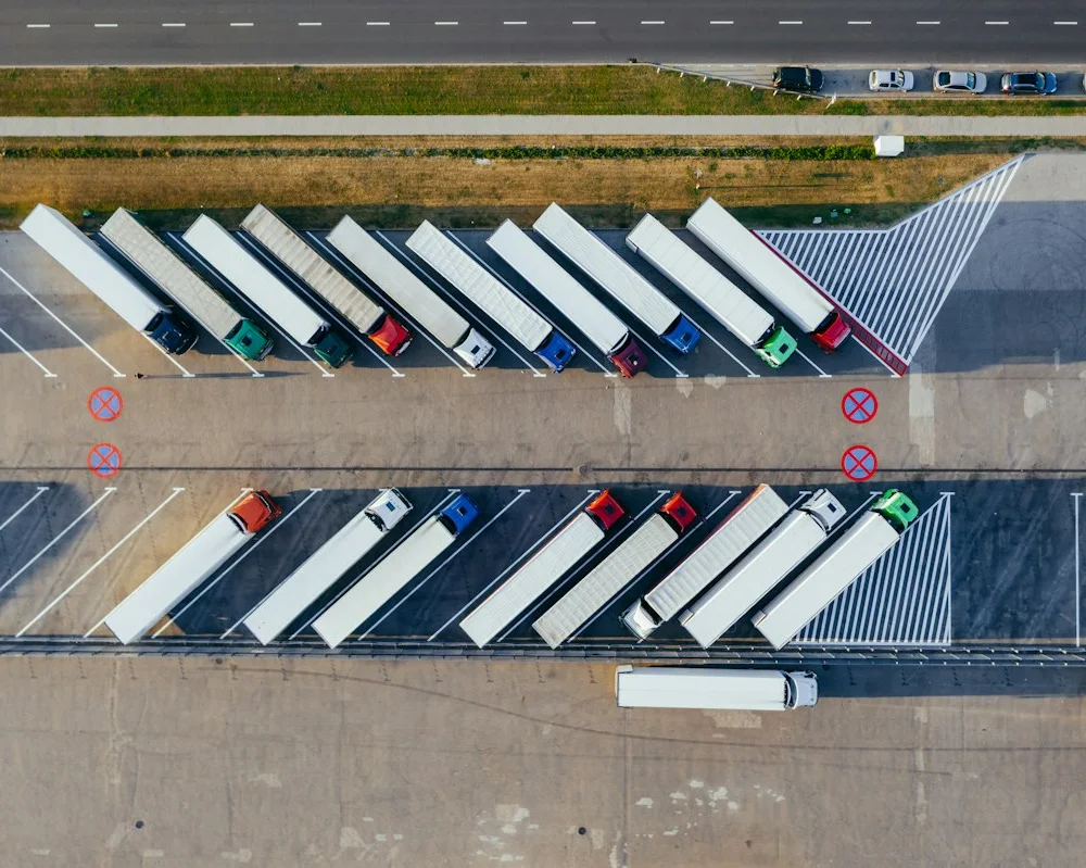 Vista aérea de vários caminhões estacionados lado a lado em duas fileiras.