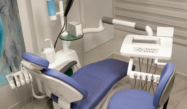 Consultório odontológico com cadeira azul e instrumentos de atendimento.